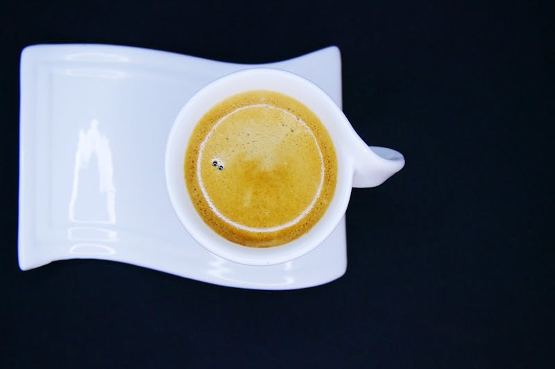 Biała filiżanka z kawą na czarnym tle