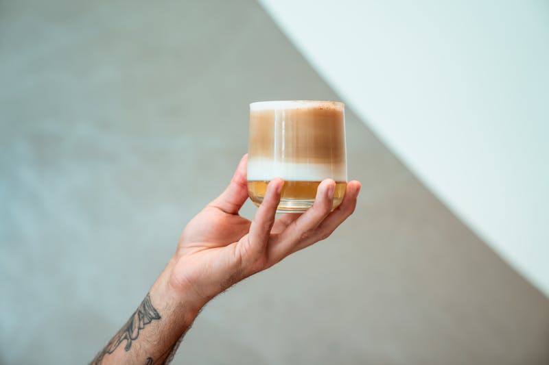 Dłoń trzymająca szklankę kawy z pianką