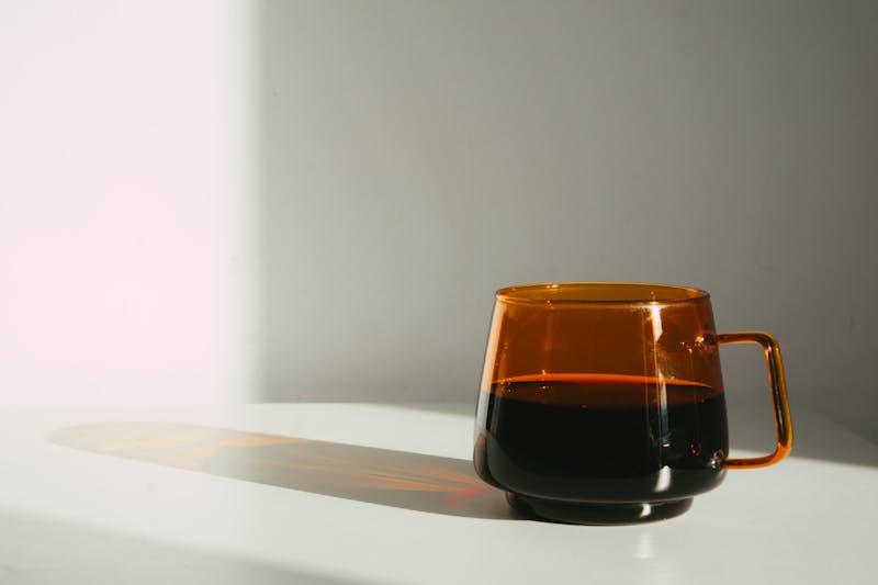 Barwiona szklanka z kawą na białym blacie